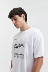 Remera blanca de manga corta con estampado frontal que incluye la palabra 'Savior' en letras cursivas negras y otros textos en tipografía sans-serif. Corte regular.
