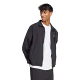 Campera deportiva Adidas de hombre, color negro, con cierre frontal y cuello alto. Presenta el logo Badge of Sport de Adidas en blanco en el lado izquierdo del pecho. Tiene puños y cintura elásticos.