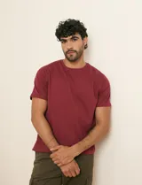 Remera básica de algodón color beige, de manga corta, con cuello redondo y un pequeño detalle bordado en el pecho.
