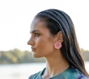 Aros tipo caravana con forma de flor grande color rosado, con brillos en el centro.