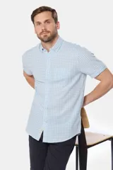 Camisa de lino de manga corta con estampado a cuadros en tonos celestes y blancos, cuello con botones y bolsillo ojal en el pecho.
