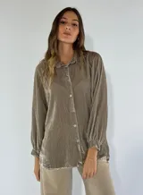 Camisa color visón de terciopelo de viscosa, con cuello clásico, cierre frontal con botones, mangas largas con puños elásticos y corte holgado.