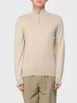 Buzo de punto fino color beige, con cuello alto y cierre frontal parcial, de manga larga y diseño clásico.