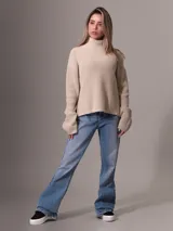 Sweater de tejido grueso con cuello alto, corte relajado y mangas largas. Presenta una textura acanalada y un diseño minimalista con etiqueta distintiva de la marca en el ruedo.