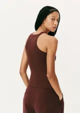 Musculosa de tejido acanalado en color naranja, con cuello redondo alto y detalle de pequeño bordado central en el pecho.