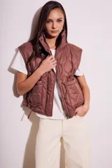 Chaleco acolchado color marrón con cierre frontal y bolsillos laterales.