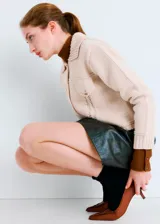 Chaqueta de punto color beige, de corte corto, con cuello camisero, bolsillos frontales con solapa y botones metálicos.