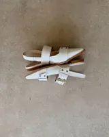 Chatas de cuero vacuno color negro, con punta fina, tira sobre el empeine con hebilla metálica y tira trasera con elástico.