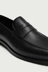 Mocasín de vestir para hombre, confeccionado en cuero marrón con diseño clásico de antifaz en el empeine, horma redonda y suela con ligero tacón.
