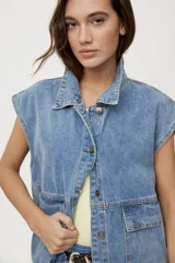 Chaleco de jean negro de calce relajado, con cuello camisero, cierre frontal con botones metálicos y bolsillos delanteros con solapa.