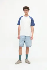 Remera estilo raglán color blanco en el cuerpo con mangas cortas color arena y cuello redondo marrón. Presenta un pequeño bordado en el pecho.