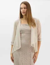 Vestido largo de encaje color beige, con escote recto decorado con pedrería y perlas, tirantes anchos y tajo lateral en la falda.