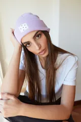 Gorro de lana color lila con etiqueta cuadrada blanca con diseño de triángulos negros.