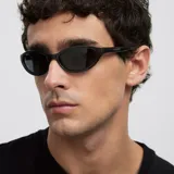 Lentes de sol con montura envolvente de diseño cat-eye en color gris traslúcido y cristales oscuros polarizados.