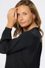Blusa de manga larga en color azul marino, con escote en V y diseño de doble capa en el frente. Presenta puños elásticos y un pequeño aplique metálico decorativo en el ruedo.