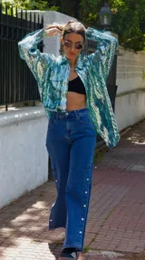 Pantalón de jean azul de tiro medio con spandex y detalle de botones metálicos en la parte inferior de la pierna.