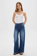 Pantalón jean gris de tiro alto, corte ancho (wide leg) con diseño de paneles tipo patchwork y terminación desmechada en el dobladillo.