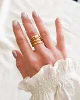 Anillo dorado de acero con diseño de cuatro bandas onduladas unidas.