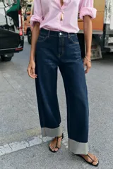 Jeans de tiro medio color azul oscuro, con cinco bolsillos, cierre de cremallera y botón. Presenta una silueta curvada, más ancha en el muslo y la rodilla, y un bajo con vuelta.