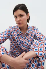 Camisa de manga larga con cuello clásico y estampa geométrica retro en tonos azul, rojo y blanco.