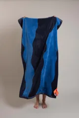 Toalla de algodón color azul con detalle de franja naranja con el nombre de la marca.