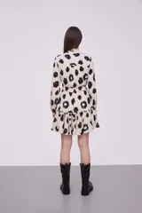 Vestido corto con estampado animal print en tonos beige, negro y azul. Tiene cuello mao, mangas largas con puños elásticos, cintura elastizada y falda con volantes.