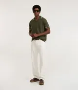 Camisa polo de manga corta color verde oliva, confeccionada en tejido de punto, con cuello y puños con ribetes contrastantes en blanco y rojo.