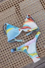 Bikini de dos piezas color marrón, con corpiño triangular fijo con corte bajo el busto, breteles regulables con hebilla y almohadillas desmontables. La bombacha es vedetina con frunce elástico en los costados.
