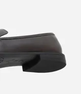 Zapato mocasín femenino de PU color negro, con punta cuadrada y detalle metálico dorado en el empeine. Tiene un tacón bajo y suela de goma.