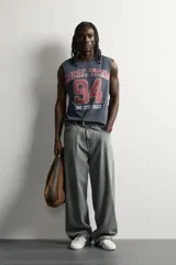Musculosa gris oscuro de ajuste relaxed, con cuello redondo y diseño sin mangas con sisa amplia. En el frente presenta una estampa estilo varsity en tonos bordó y blanco con la inscripción "Local Team 94 One Step Daily".
