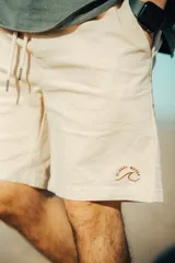 Bermuda color beige con cordón ajustable en la cintura y logo bordado en la pierna derecha.