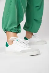Zapatillas acordonadas de cuero color blanco con puntera de gamuza gris y detalles en verde.