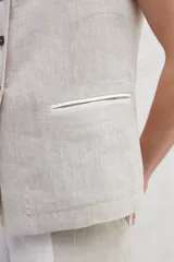 Chaleco azul de lino con cuello mao, abotonado al frente y bolsillos ojal con ribete blanco.