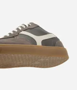 Championes de estilo deportivo tipo chutera, confeccionados en poliuretano con recortes en contraste. Presentan punta redondeada, cordones bicolores y suela plana color caramelo.