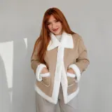 Campera gamulán corta para mujer, de color beige con forro y detalles de corderito blanco en el cuello, solapa frontal, bolsillos y puños. Cuenta con cierre frontal de botones y dos bolsillos delanteros con solapa.
