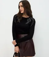 Suéter de punto en color negro con cuello redondo y mangas largas. Presenta un delicado bordado floral con pedrería en la zona de los hombros.