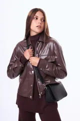 Campera de cuero sintético color marrón chocolate, con cierre frontal y botones a presión, cuello camisero y bolsillos frontales con solapa.