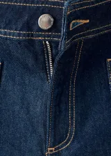 Pantalón wide leg de denim azul oscuro, de tiro alto con trabillas y cierre frontal de cremallera y botón. Presenta bolsillos de parche delanteros.