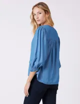 Blusa Zac & Rachel de lyocell color azul, con escote en V y panel central con pespuntes. Presenta mangas tres cuartos abullonadas con frunces en los hombros y puños elastizados con detalle de volante.