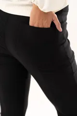 Pantalón de vestir negro de corte acampanado, con cintura de tiro medio, cierre frontal con botón y bolsillos laterales.