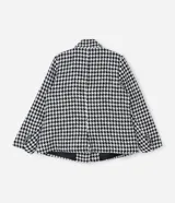 Blazer de sastrería confeccionado en tejido tweed con estampado pied de poule en blanco y negro. Presenta cuello con solapa, cierre frontal con un botón, mangas largas y bolsillos frontales con solapa.