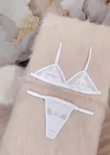 Conjunto de lencería compuesto por un corpiño triangular de microtul transparente con detalles de encaje floral y una tanga regulable a juego.