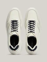Zapatillas Tommy Hilfiger de cuero color blanco con detalles en azul marino. Presentan cordones azul marino, suela gruesa blanca y logo de la marca en el lateral.