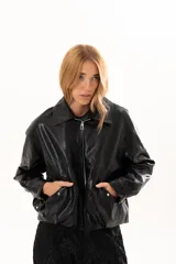 Campera de cuero sintético color negro, con cierre frontal, cuello clásico y bolsillos laterales con broches metálicos.
