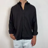 Camisa de manga larga confeccionada en lino, color blanco, con cuello clásico y cierre frontal de botones.
