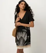 Vestido corto negro de viscosa y lino, con escote en V, mangas cortas y estampa gráfica de follaje blanco en la parte inferior, complementada con franjas horizontales en el ruedo.