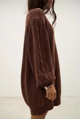 Vestido corto de punto color chocolate, con diseño de trenzas en las mangas, cuello redondo y corte holgado.