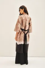 Kimono largo estampado con diseño floral, de corte recto y mangas amplias 3/4. Presenta un diseño de bloques de color con una base en tonos tierra y un borde inferior en color negro.