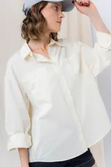 Camisa verde pastel de algodón, corte oversize, con cuello camisero, cierre con botones, mangas largas con puños con volados de encaje blanco, dos bolsillos frontales con solapa y ruedo irregular. 