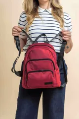 Mochila urbana de diseño funcional en color beige, confeccionada en tela impermeable. Cuenta con un compartimento principal amplio, un bolsillo secundario y un bolsillo frontal, todos con cierre. Incluye asa superior y correas ajustables para los hombros, con detalle de etiqueta de marca en el frente.